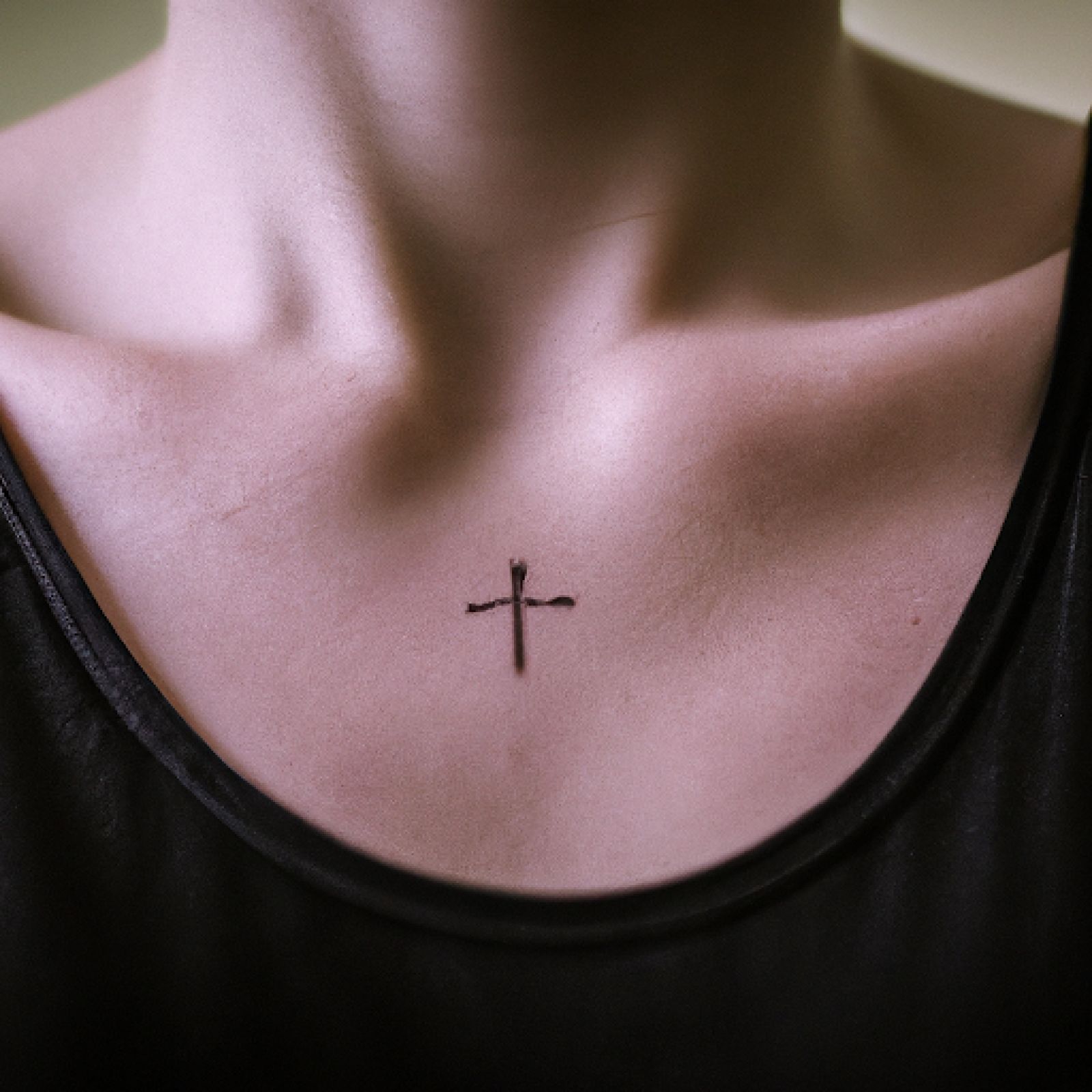 Cross tattoo on sternum for women