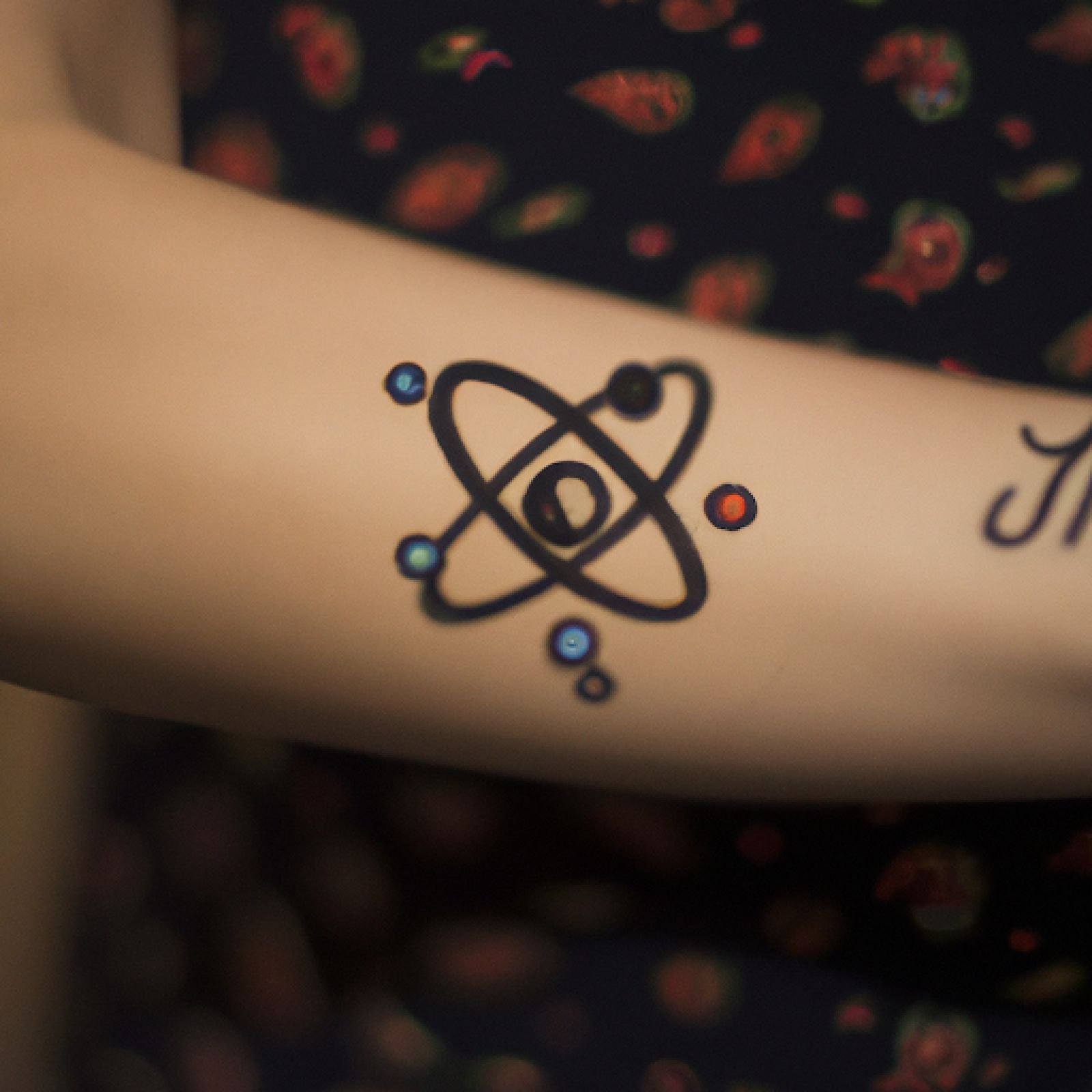 Atom tattoo on arm for women