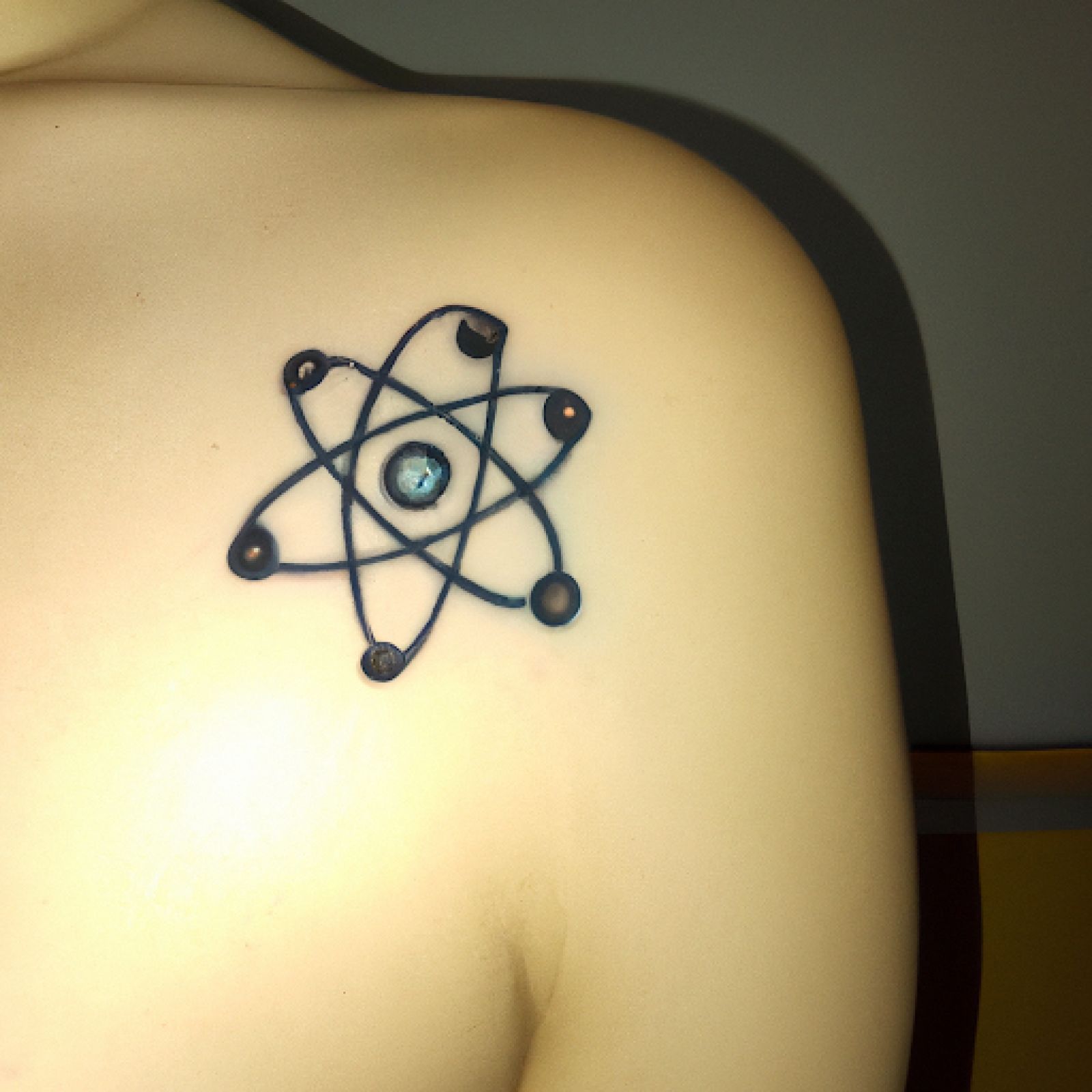 Atom tattoo on back for women