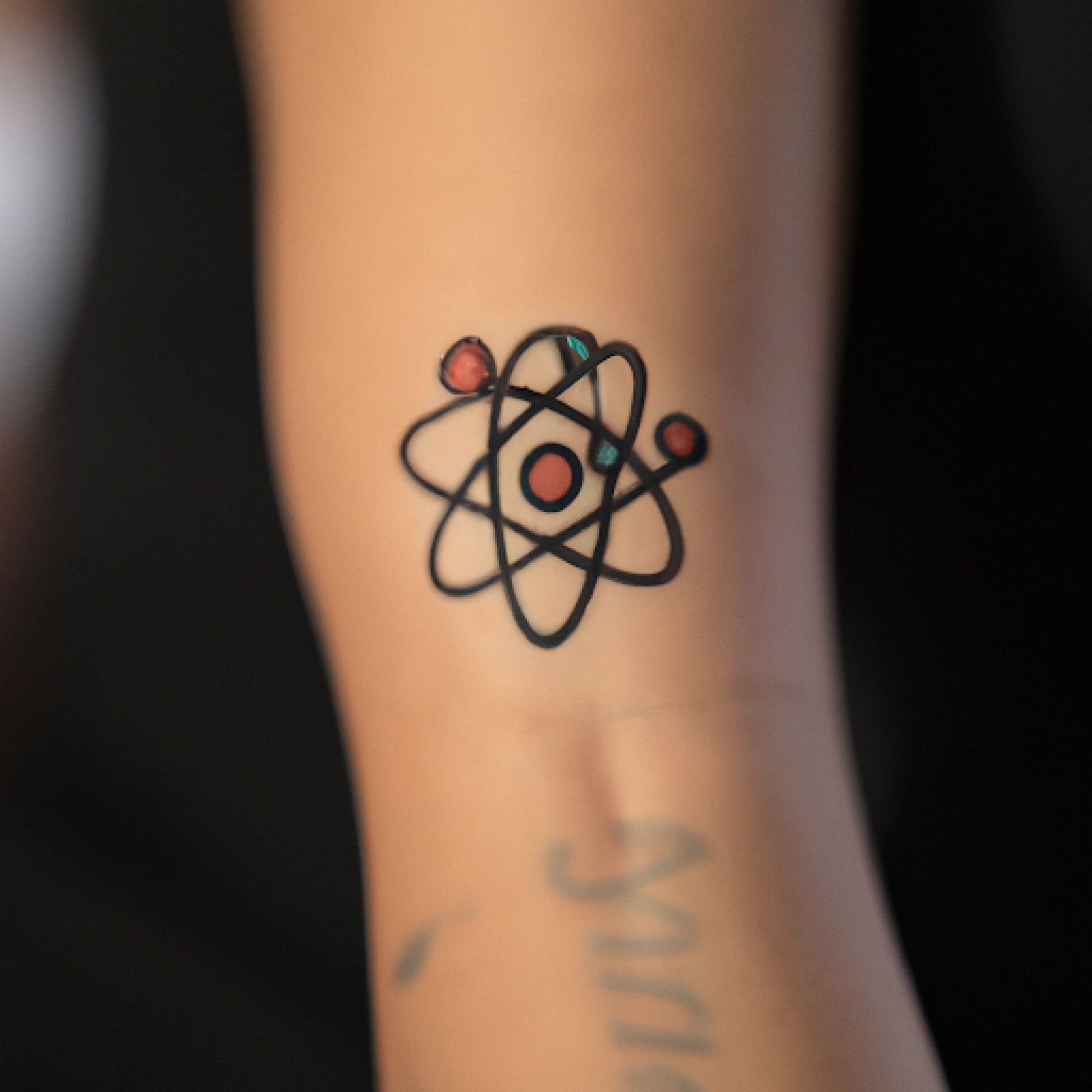 Atom tattoo on forearm for women