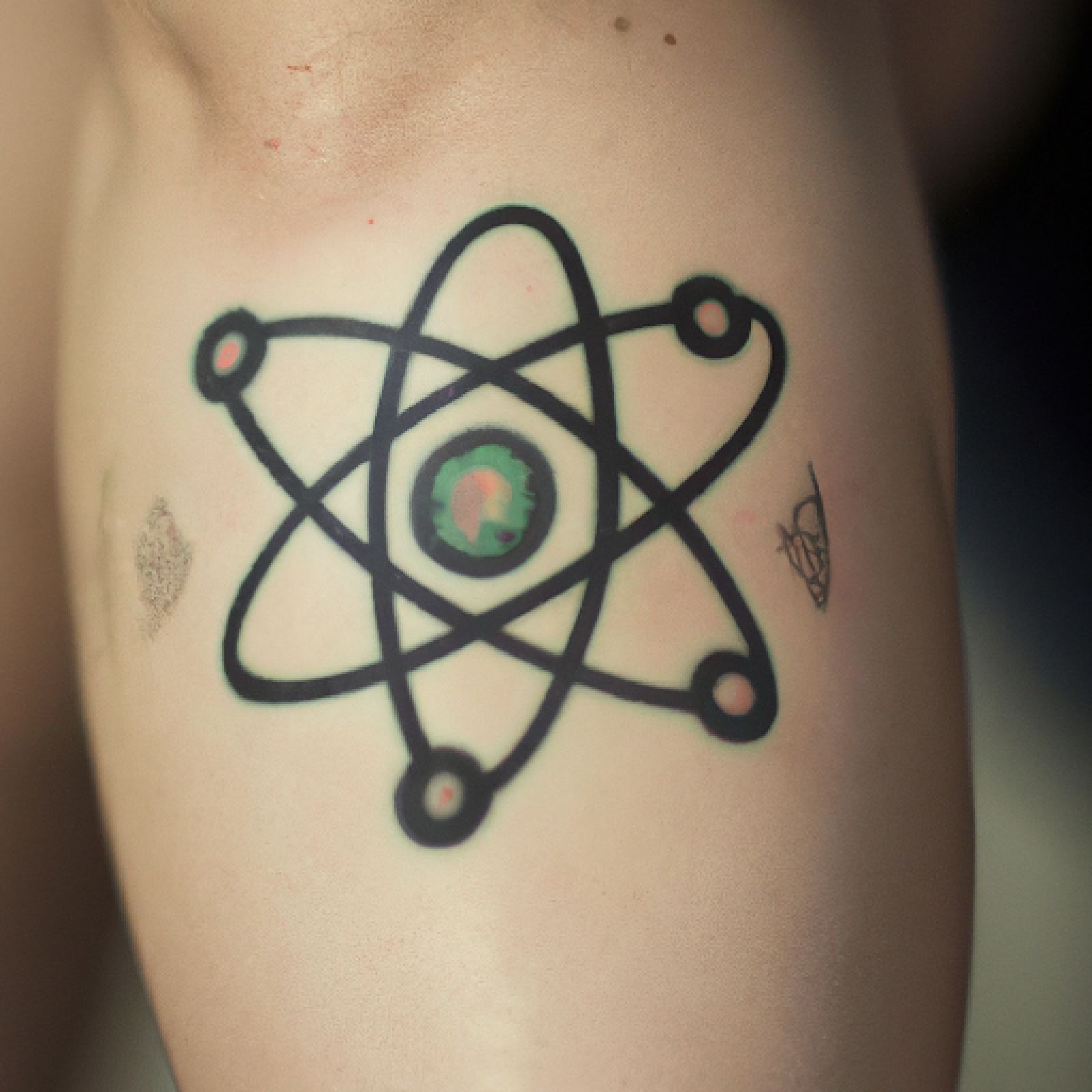 Atom tattoo on knee for women