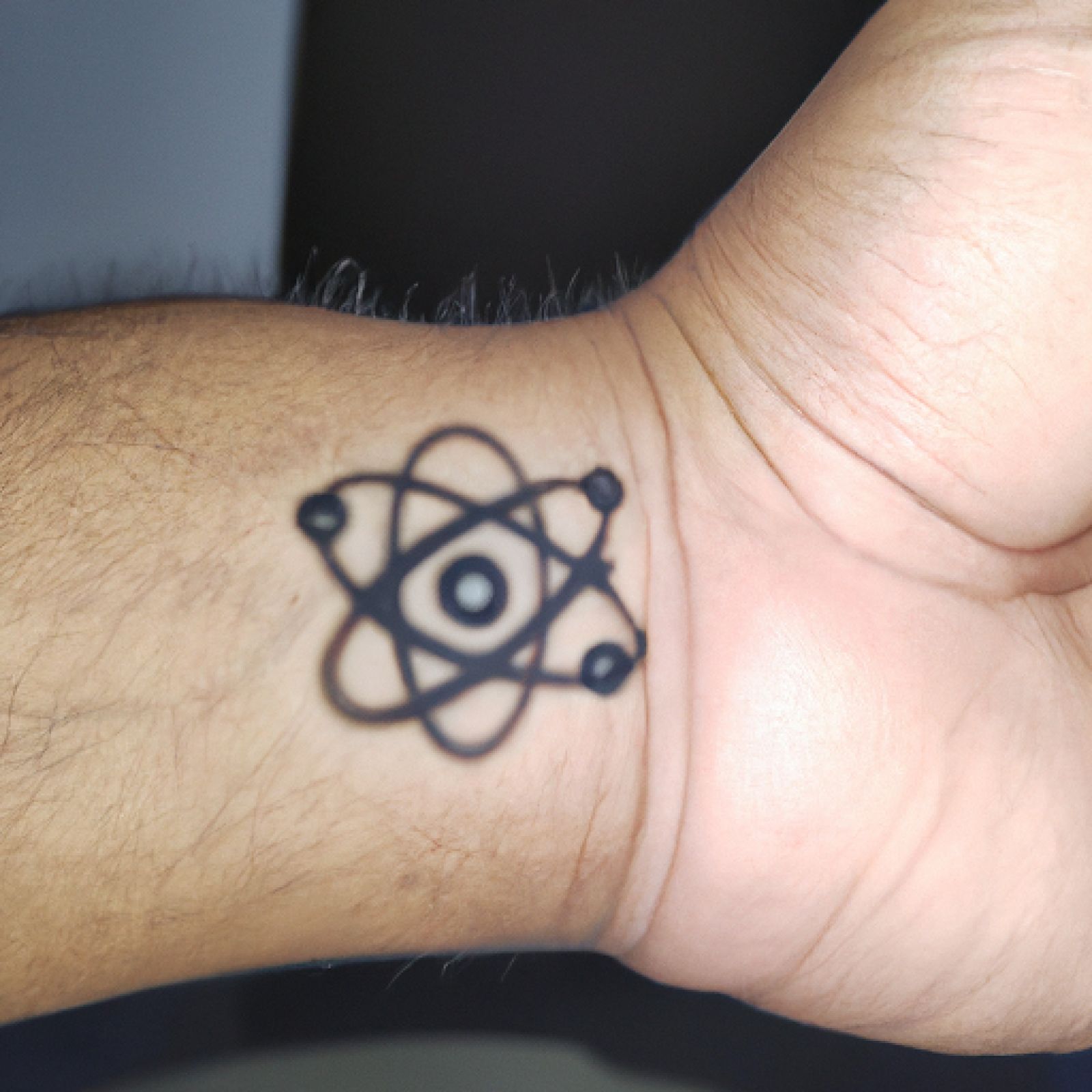 Atom tattoo on wrist for men