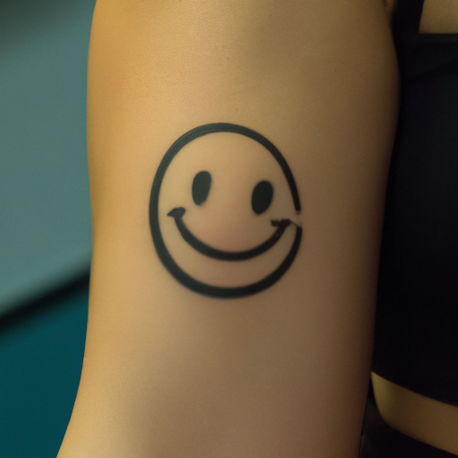 Smiley tattoo on arm for women