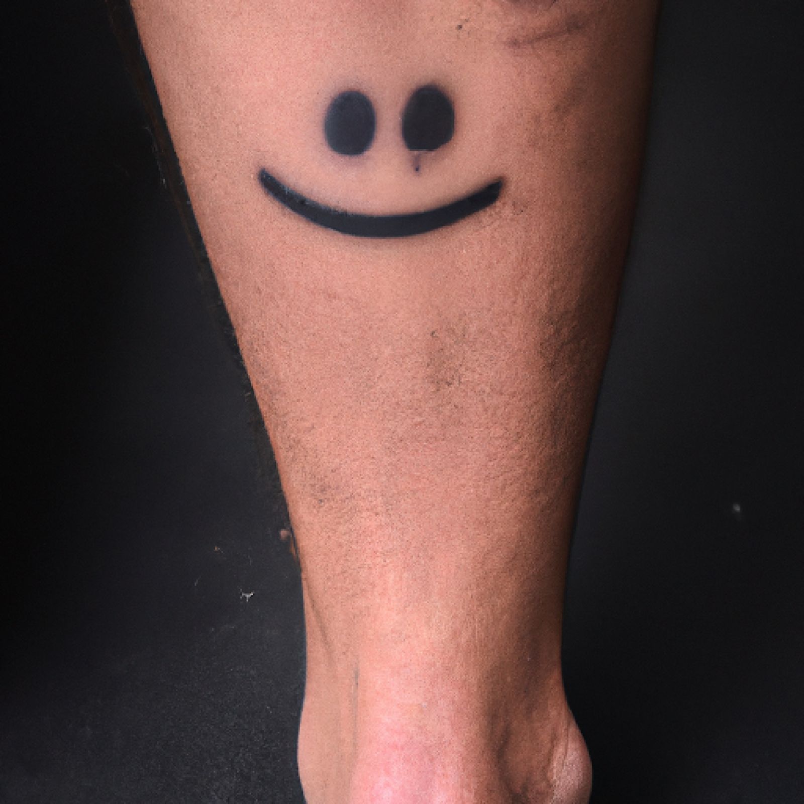 Smiley tattoo on calf for men