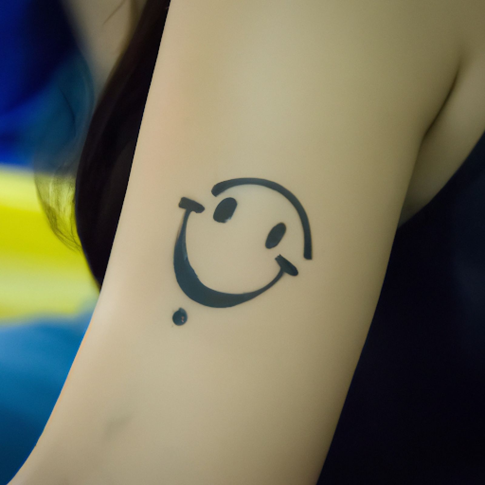Smiley tattoo on forearm for women