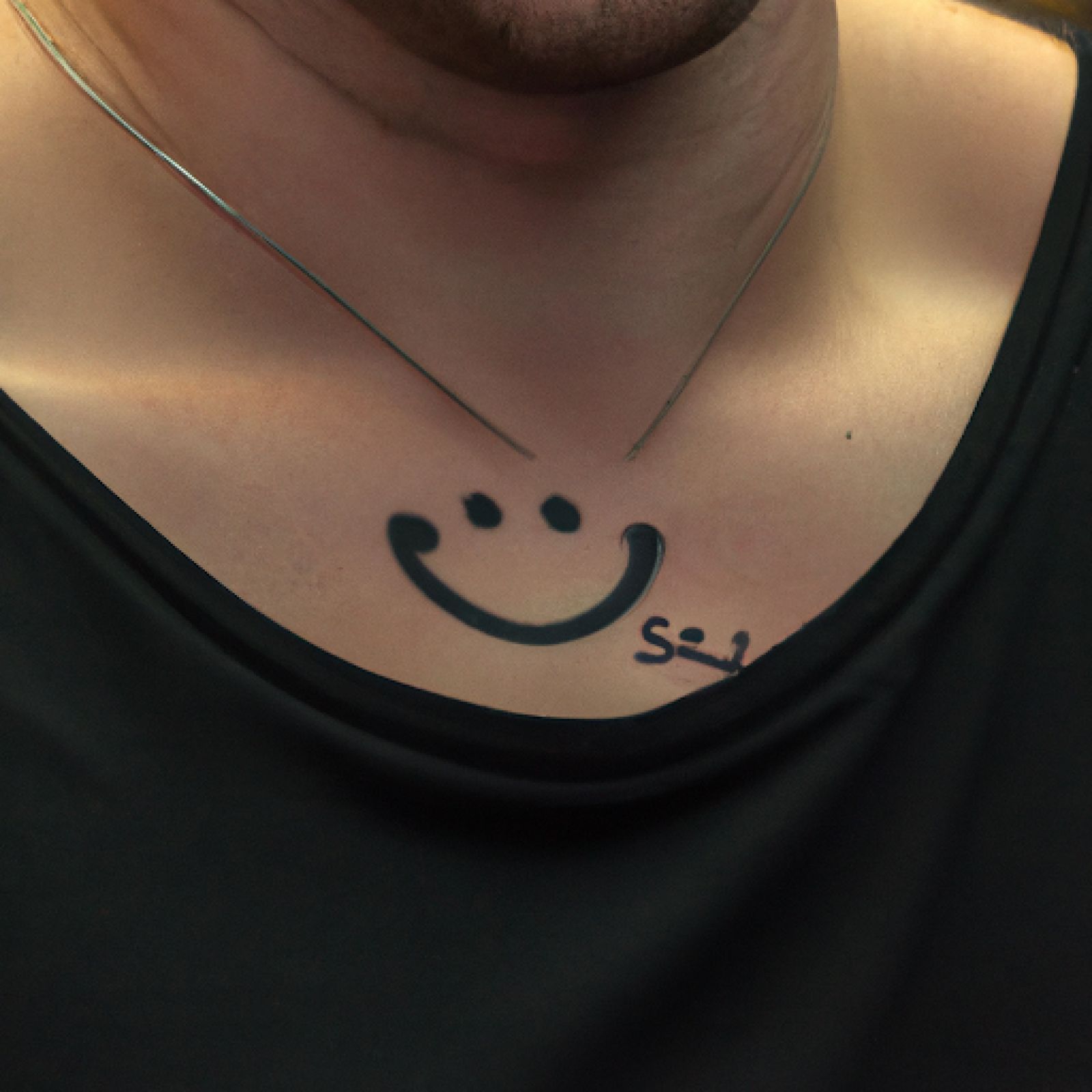 Smiley tattoo on sternum for men