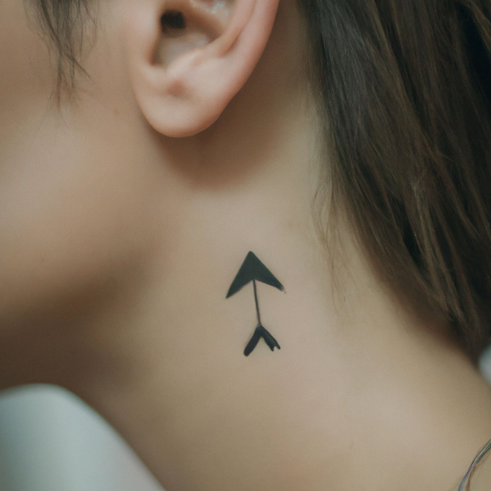 Arrow tattoo on neck for women